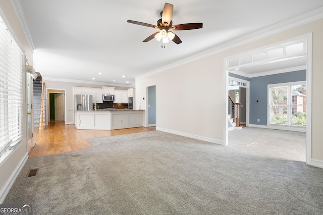 unfurnished living room with crown molding, light colored carpet, and ceiling fan