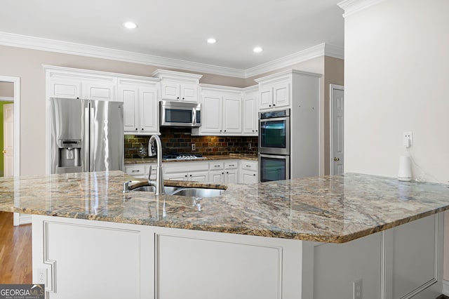 kitchen featuring appliances with stainless steel finishes, sink, kitchen peninsula, white cabinetry, and light stone counters