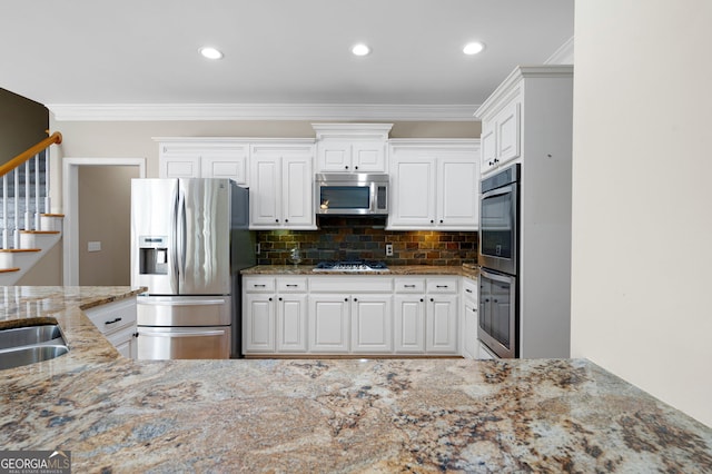 kitchen featuring white cabinetry, light stone countertops, stainless steel appliances, and backsplash