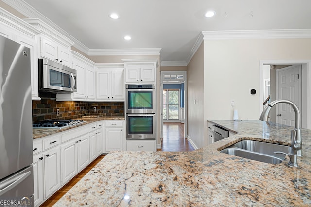 kitchen with white cabinetry, light stone counters, stainless steel appliances, and hardwood / wood-style floors