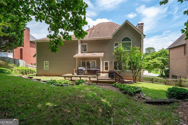 rear view of property featuring a deck and a lawn