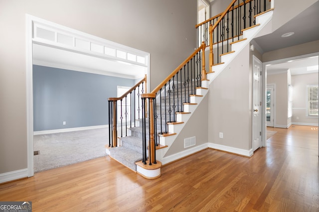 staircase featuring ornamental molding and hardwood / wood-style floors