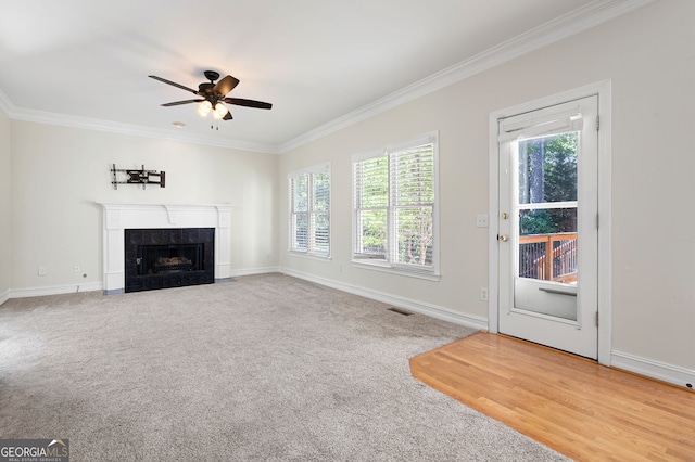 unfurnished living room with crown molding, a wealth of natural light, and a tile fireplace