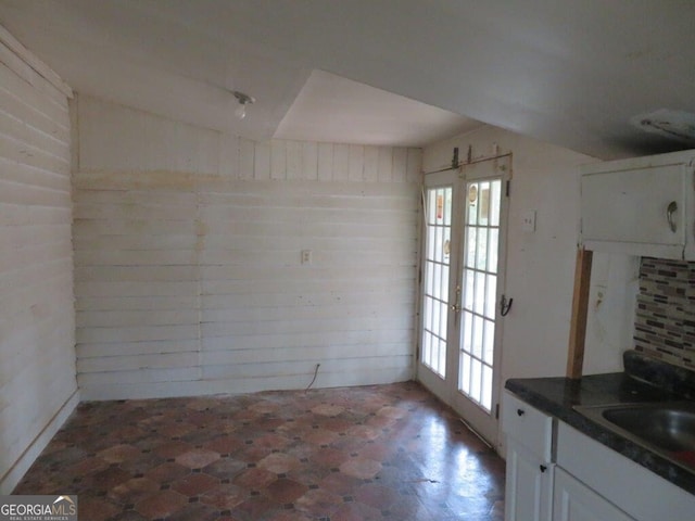 unfurnished dining area featuring sink, wooden walls, and french doors
