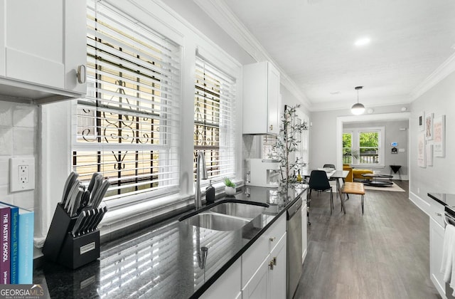 kitchen with dark stone countertops, stainless steel dishwasher, sink, white cabinetry, and hanging light fixtures