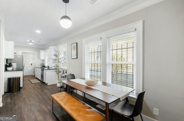 dining area featuring dark wood-type flooring, ornamental molding, and sink