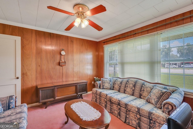 carpeted living room featuring ceiling fan, wood walls, and ornamental molding