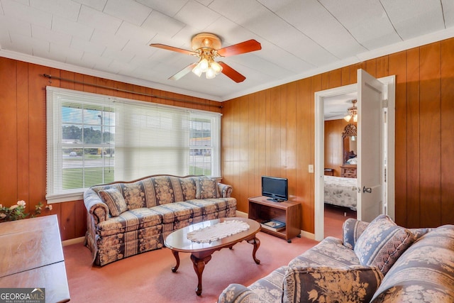 living room featuring wood walls, carpet, ornamental molding, and ceiling fan