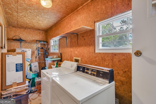 clothes washing area featuring washer and clothes dryer and wooden walls