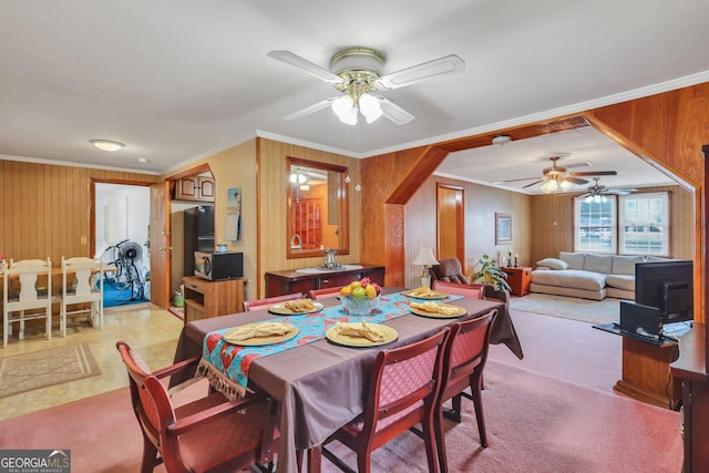 dining room with light carpet, wood walls, and ornamental molding