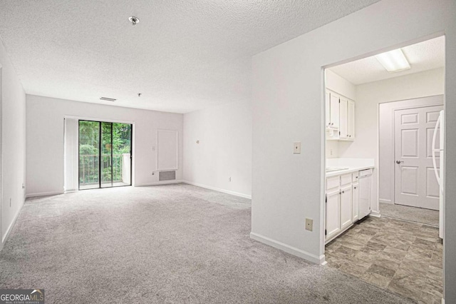 empty room featuring light carpet and a textured ceiling