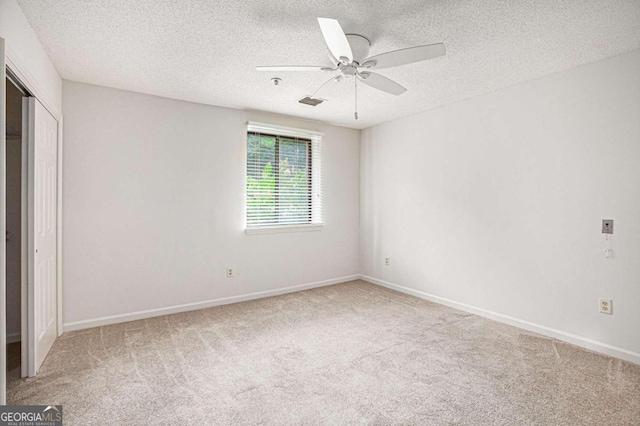 spare room featuring light colored carpet, a textured ceiling, and ceiling fan