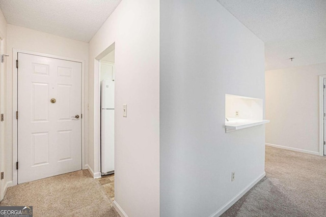 hall with light colored carpet and a textured ceiling