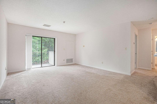 unfurnished room with light colored carpet and a textured ceiling