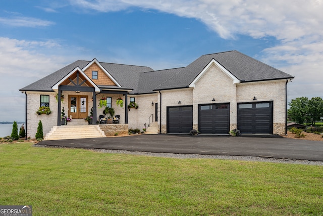 view of front of home with covered porch, a garage, and a front lawn