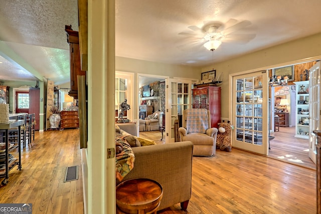 living room featuring ceiling fan, a textured ceiling, and light hardwood / wood-style flooring