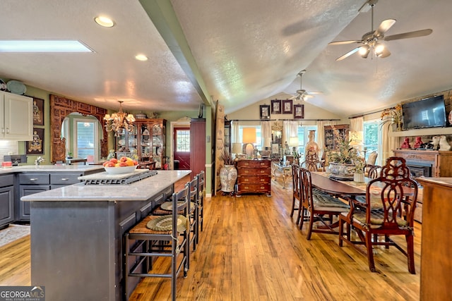 kitchen with light hardwood / wood-style floors, ceiling fan with notable chandelier, gray cabinets, and lofted ceiling