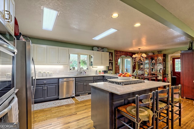 kitchen with light hardwood / wood-style floors, a breakfast bar area, stainless steel appliances, and gray cabinetry