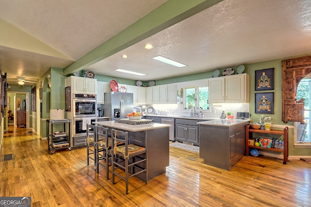 kitchen featuring a kitchen island, appliances with stainless steel finishes, a textured ceiling, and light hardwood / wood-style floors