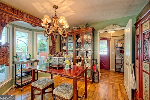 dining space with a notable chandelier, a textured ceiling, and hardwood / wood-style flooring