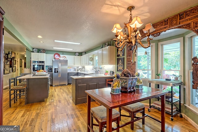 kitchen featuring a notable chandelier, light hardwood / wood-style flooring, appliances with stainless steel finishes, and a kitchen island