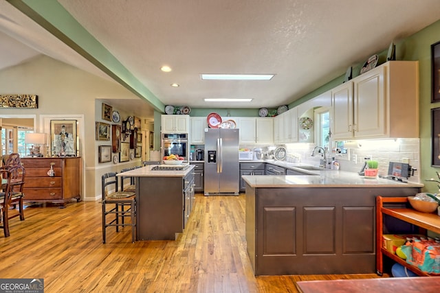 kitchen with a kitchen breakfast bar, light wood-type flooring, and stainless steel appliances