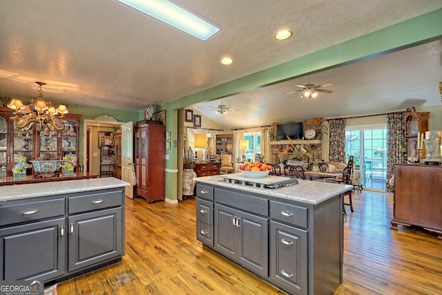 kitchen featuring lofted ceiling with beams, light hardwood / wood-style flooring, ceiling fan with notable chandelier, and gray cabinets