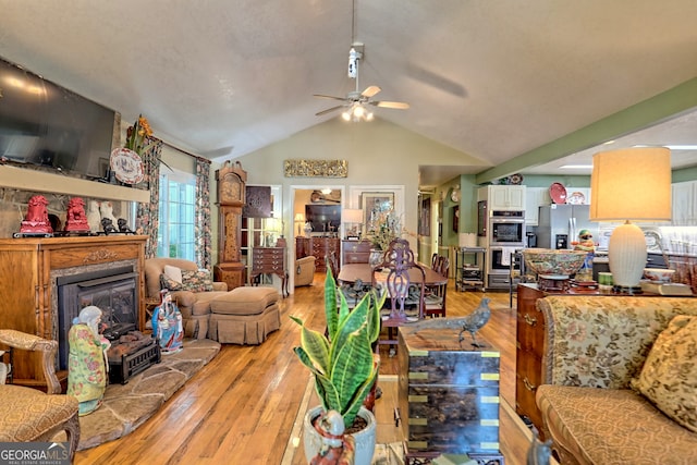 living room with ceiling fan, light hardwood / wood-style flooring, and vaulted ceiling