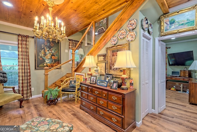 living area with wood ceiling, ornamental molding, a notable chandelier, and hardwood / wood-style floors