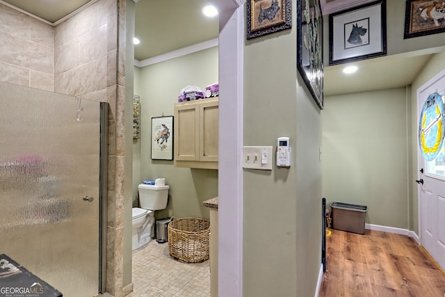 bathroom with a shower with shower door, toilet, hardwood / wood-style flooring, and crown molding