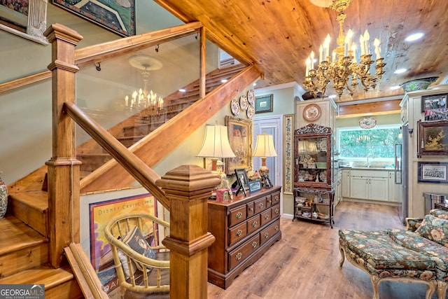 stairs with a notable chandelier, wood-type flooring, crown molding, and wood ceiling