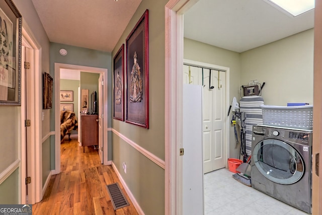 clothes washing area with light hardwood / wood-style flooring and washer / clothes dryer