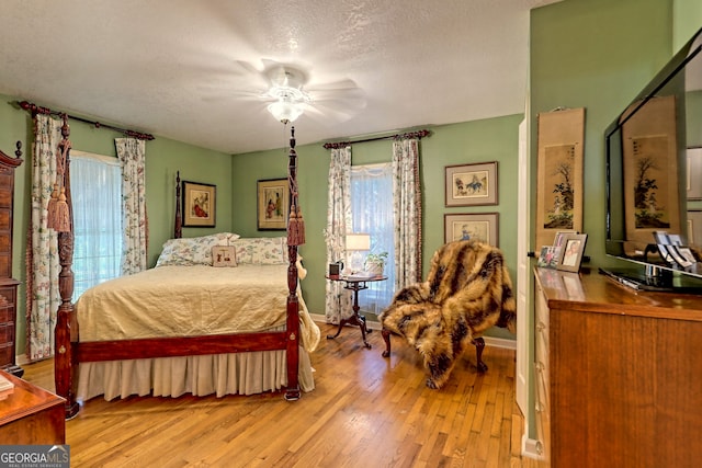 bedroom featuring ceiling fan, a textured ceiling, and light hardwood / wood-style flooring