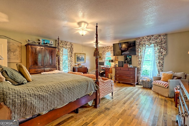 bedroom with light wood-type flooring, a textured ceiling, and ceiling fan