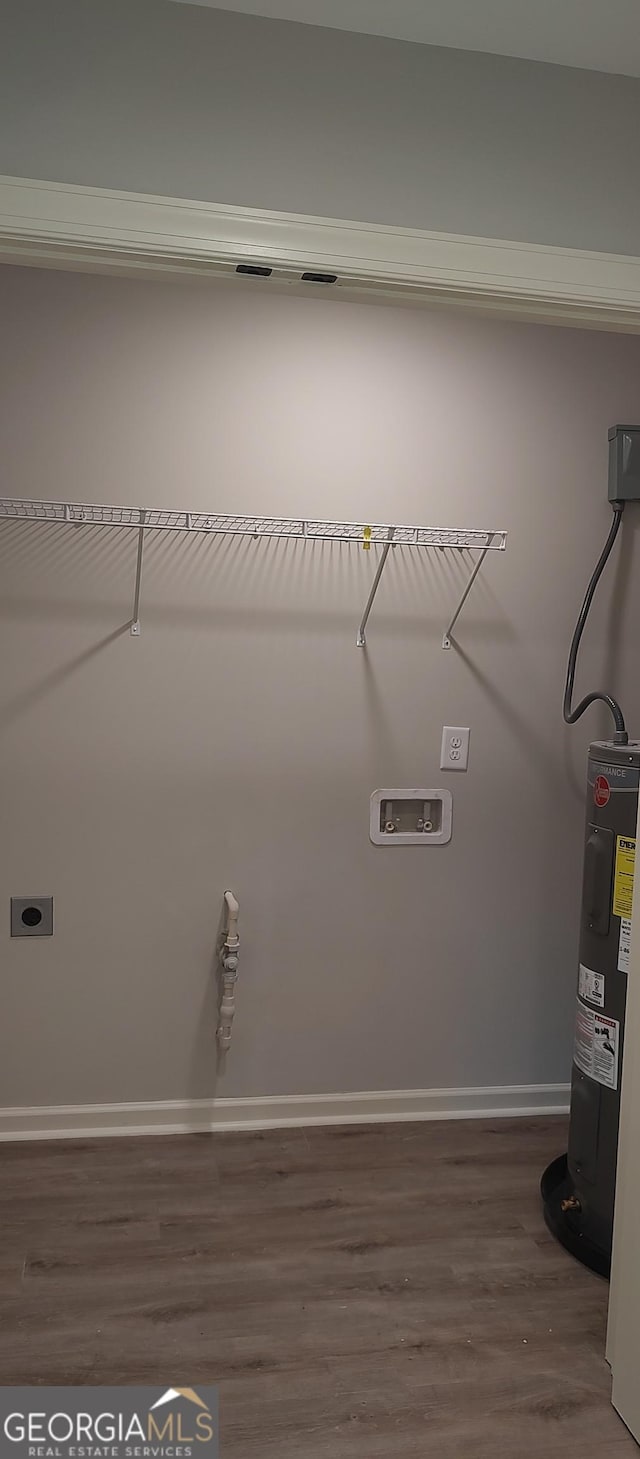 clothes washing area with dark hardwood / wood-style flooring, electric dryer hookup, and water heater