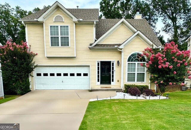 view of front of home featuring a garage, central AC, and a front yard