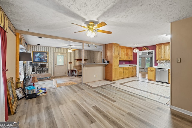 kitchen with pendant lighting, dishwasher, a textured ceiling, kitchen peninsula, and light hardwood / wood-style flooring