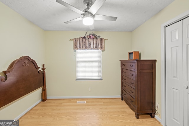 bedroom with ceiling fan, a textured ceiling, a closet, and light hardwood / wood-style floors