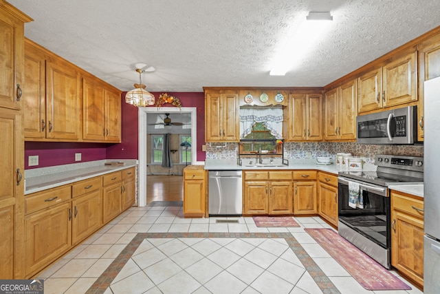 kitchen featuring ceiling fan, hanging light fixtures, light tile patterned floors, a textured ceiling, and appliances with stainless steel finishes