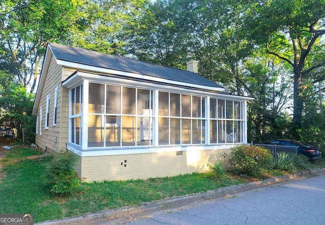 view of home's exterior with crawl space, a chimney, and a sunroom
