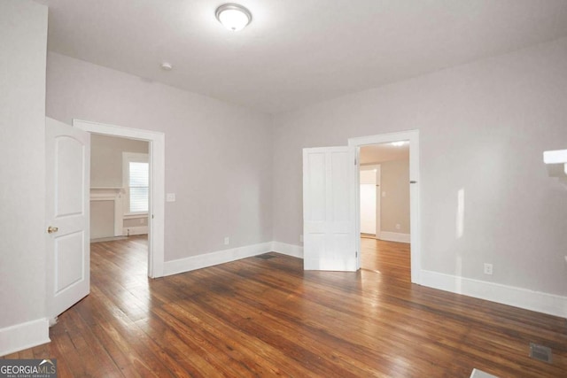 unfurnished room with visible vents, hardwood / wood-style flooring, and baseboards