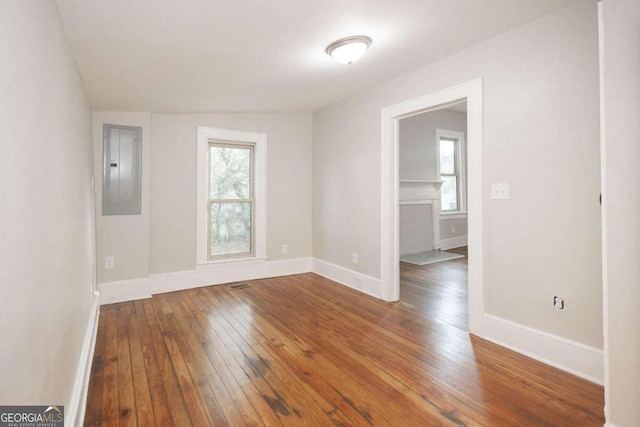 spare room featuring wood-type flooring, baseboards, and electric panel