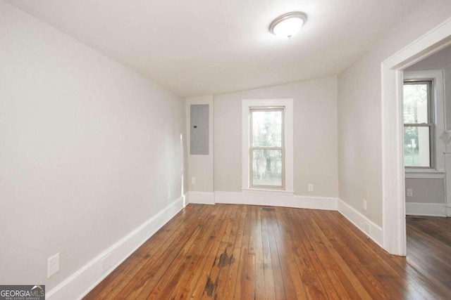 unfurnished room with electric panel, vaulted ceiling, baseboards, and wood-type flooring