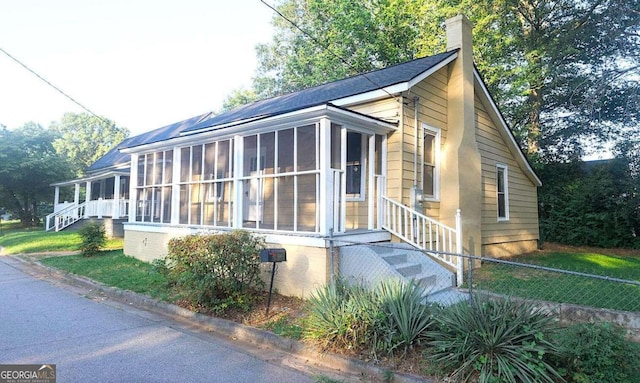 view of front facade with fence, a chimney, a sunroom, and stairs