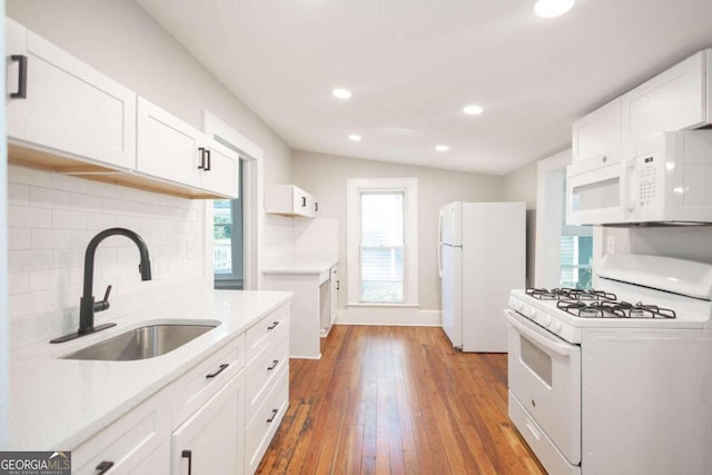 kitchen featuring white cabinetry, hardwood / wood-style flooring, backsplash, white appliances, and sink