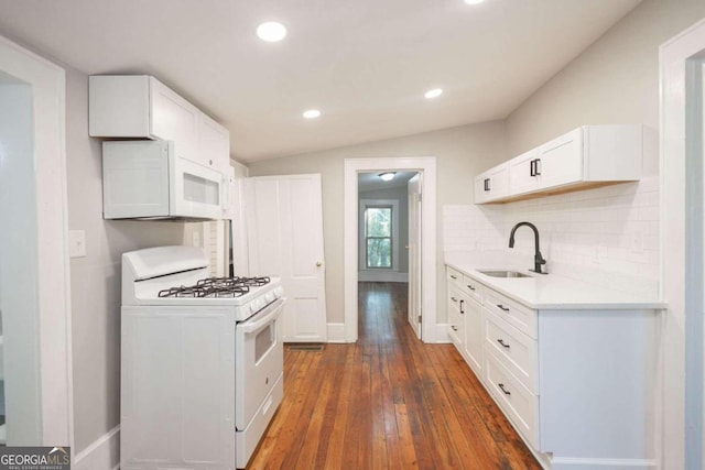 kitchen featuring white appliances, white cabinets, dark hardwood / wood-style flooring, sink, and vaulted ceiling