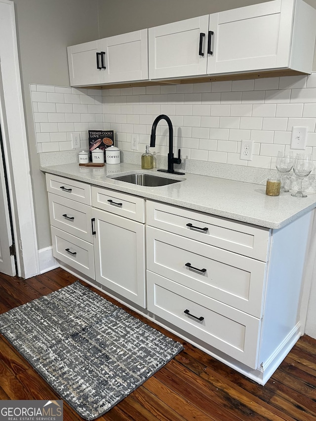 kitchen featuring dark wood finished floors, tasteful backsplash, a sink, and white cabinetry