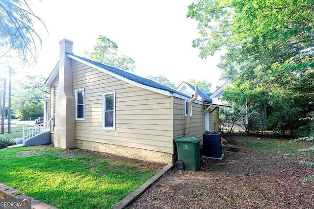 view of property exterior featuring a lawn, a chimney, and cooling unit