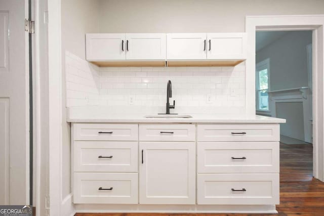 bar with dark wood-style floors, a sink, and tasteful backsplash