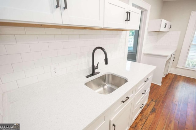 kitchen with dark wood-type flooring, tasteful backsplash, white cabinetry, and a sink